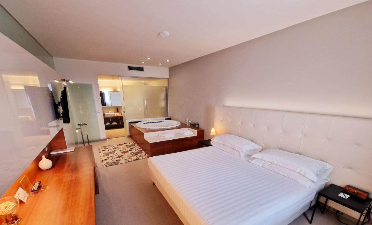 Camera moderna con letto matrimoniale e vasca idromassaggio.